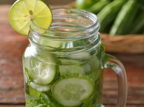 Cucumber water in mason jar with lime slice.