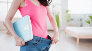woman holding scale and showing weight loss featured
