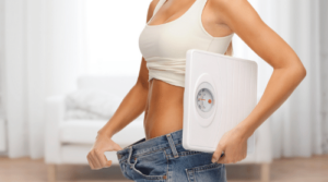 woman with loose pants holding scale weight loss featured