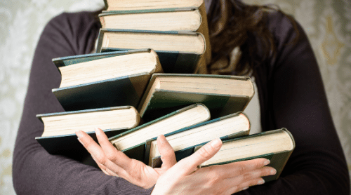 woman holding stack of books featured