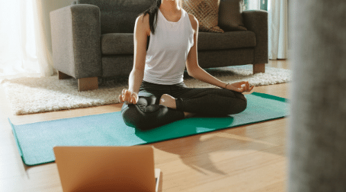 woman doing yoga with yoga video on computer featured