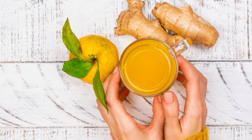 woman holding tea cup with lemon and ginger featured