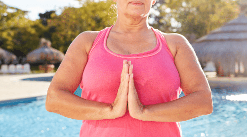 older woman doing yoga by a pool featured