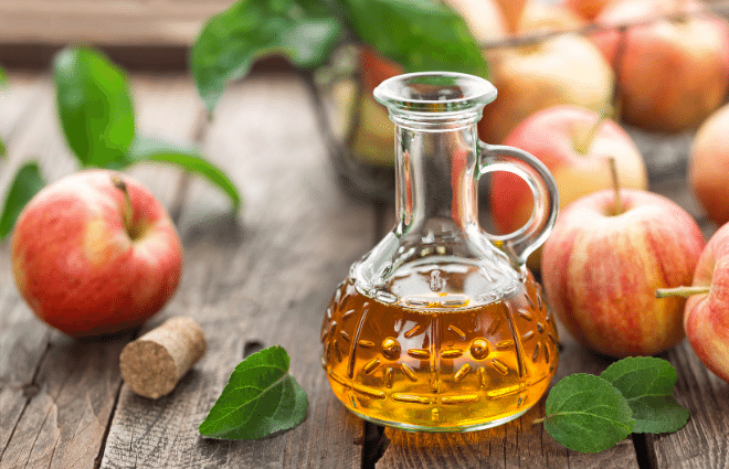 apple cider vinegar in a bottle with fresh apples and leaves