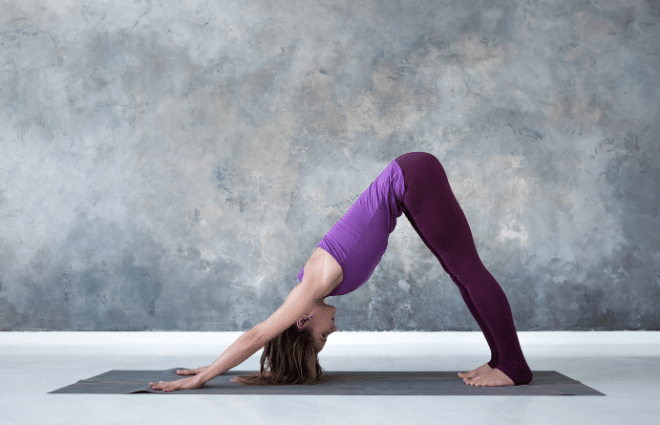 woman in purple outfit doing downward dog yoga pose