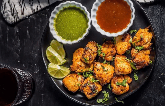 grilled chicken tikka with green and red sauce on the side