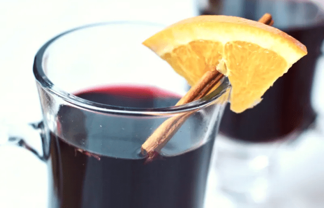 glass mug of hot mulled red wine with orange slice and cinnamon stick