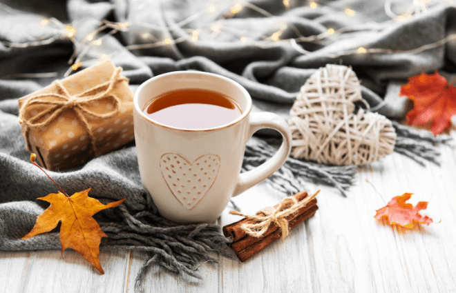 cozy holiday self care scene, tea and fall leaves
