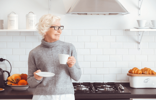 older woman drinking coffee in a kitchen