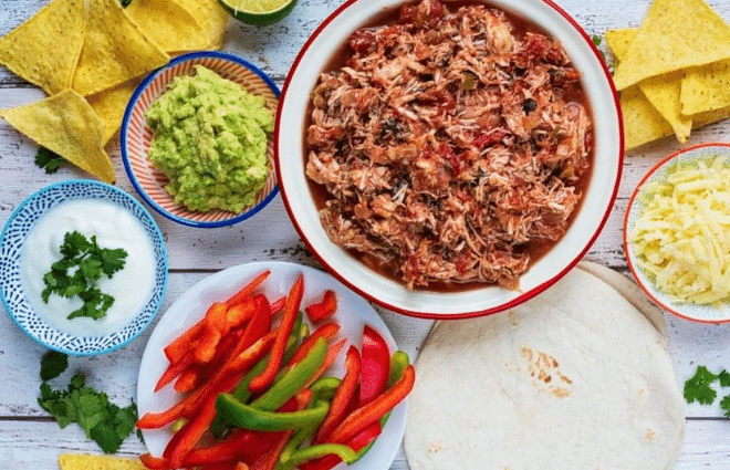 slow cooker salsa chicken in bowl with peppers and sides