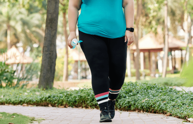 overweight woman in blue shirt and black pants walking to lose weight for insulin resistance