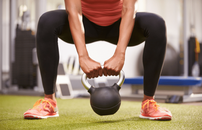 woman doing a squat with a kettlebell