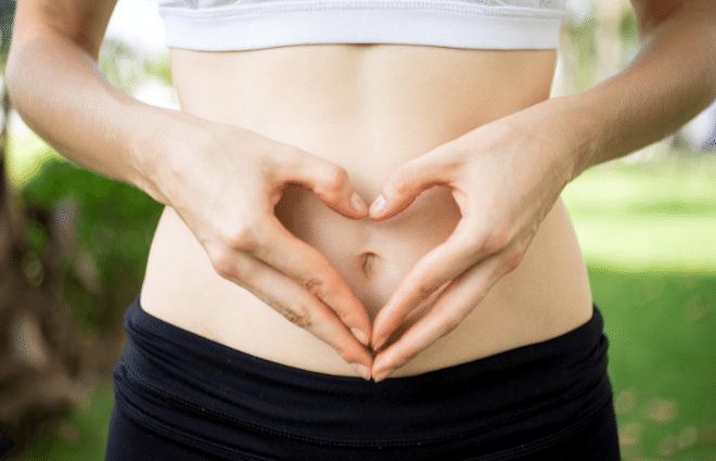 A woman making a heart shape in front of her stomach