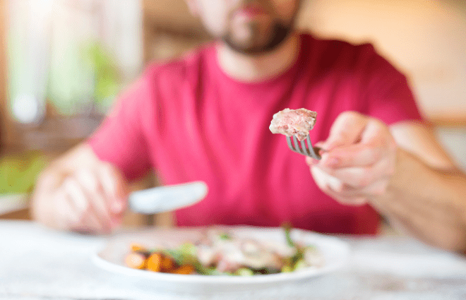 Man eating chicken while sitting a table