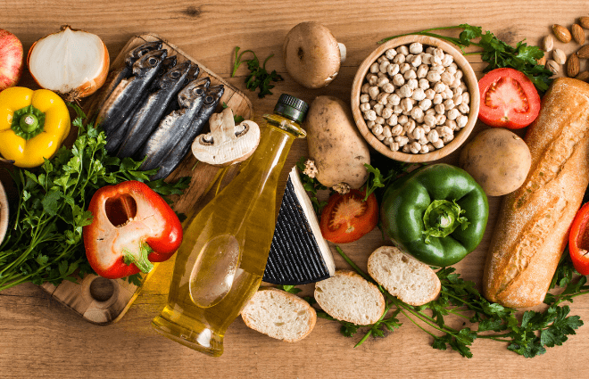 Healthy vegetables, bread, fish, beans, and olive oilon a table