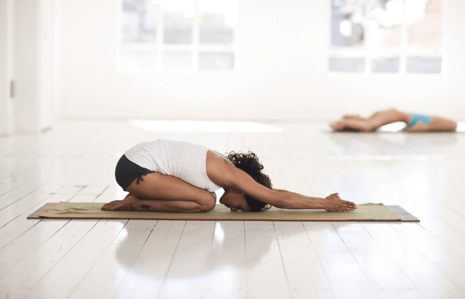 Woman on yoga mat in child's yoga pose