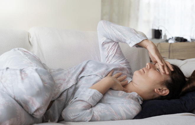 Woman experience chronic illness, laying down with pajamas on